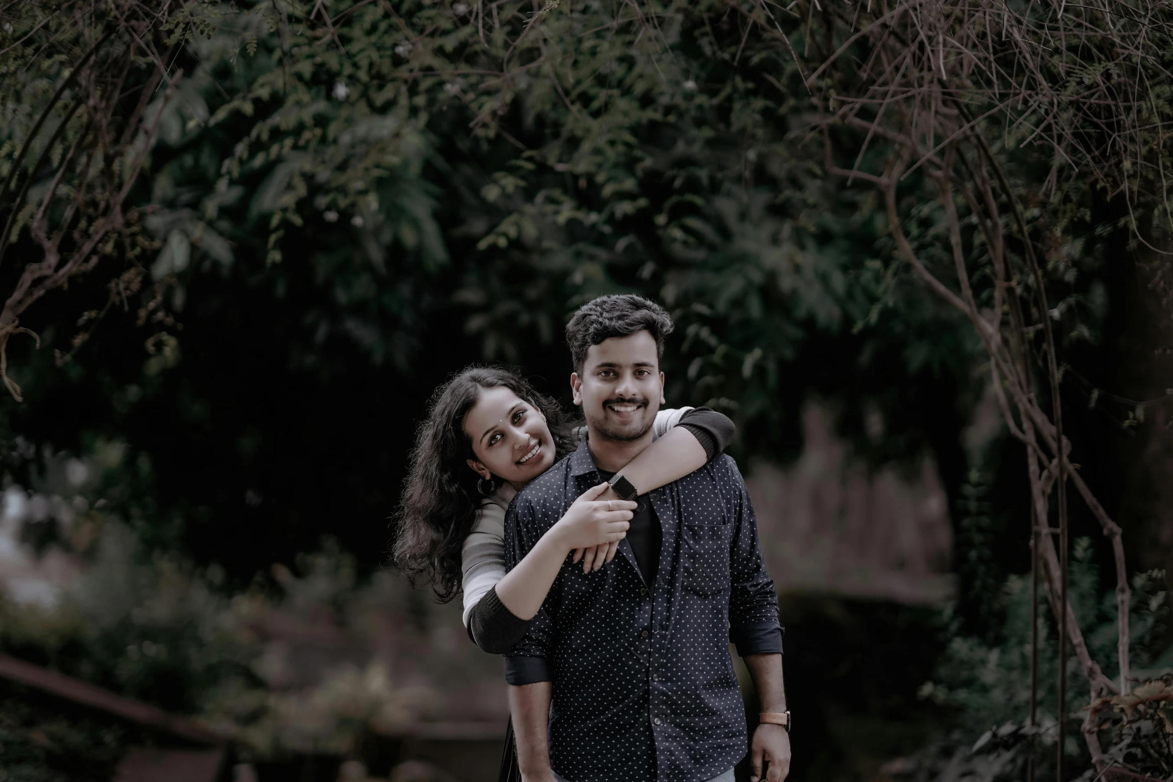 two people standing together with trees in the background