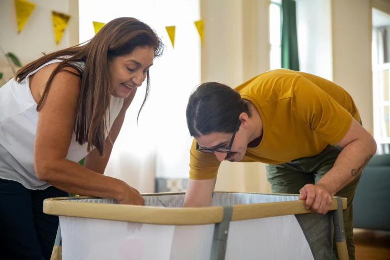 a man and woman bending over looking a baby in a crib