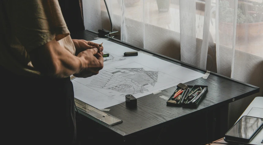 a man is drawing with markers on a table