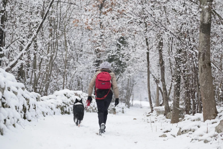 a man with backpack walking down snow covered road