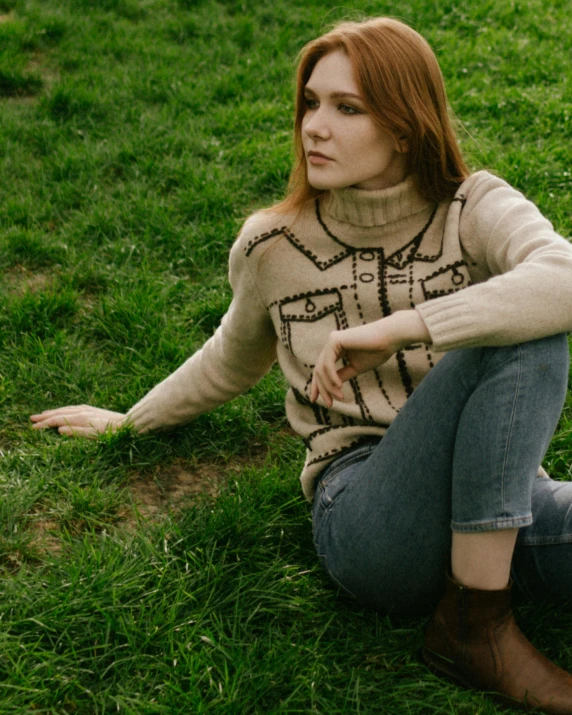 a red headed woman sits in the grass