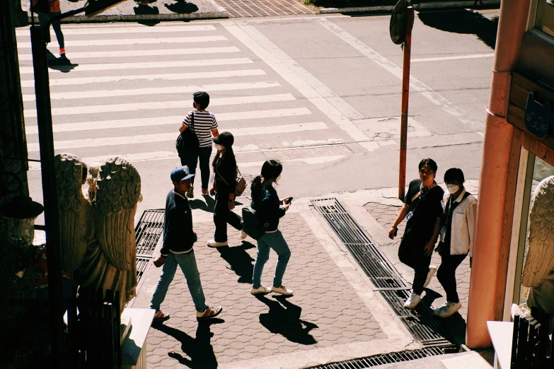a group of people walking across a sidewalk near an intersection