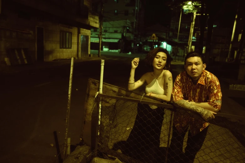 a man and woman standing by a fence on a dark night