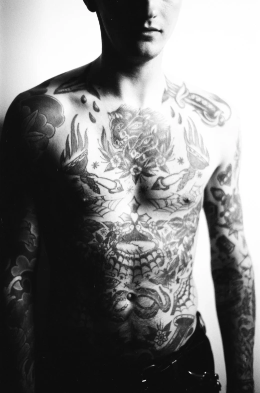 a man with large tattoos stands behind a door