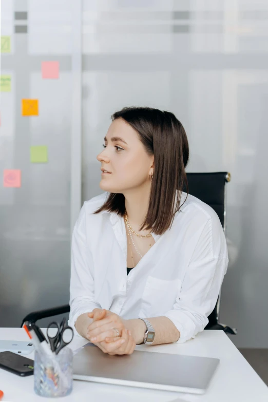 the woman is sitting at the desk with her hands folded on the desk