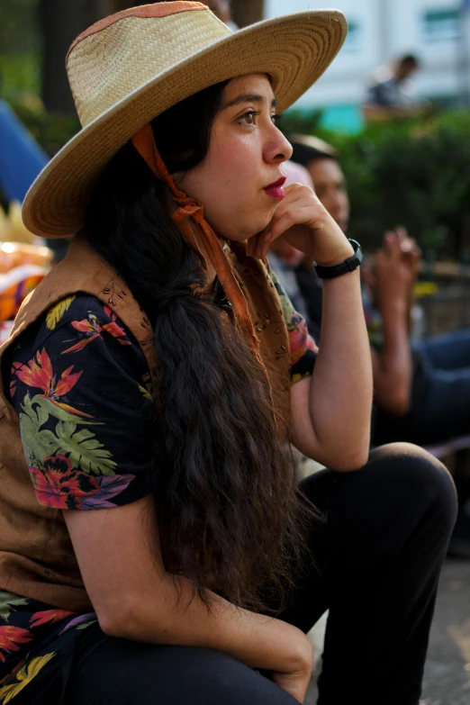 the woman is wearing a big hat while sitting