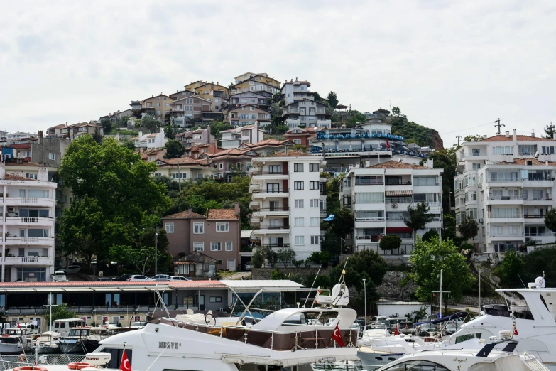 boats docked in a large city harbor with apartment buildings behind them