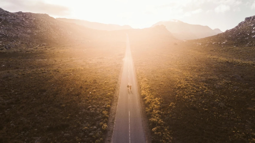 an aerial view of a country road near some mountains