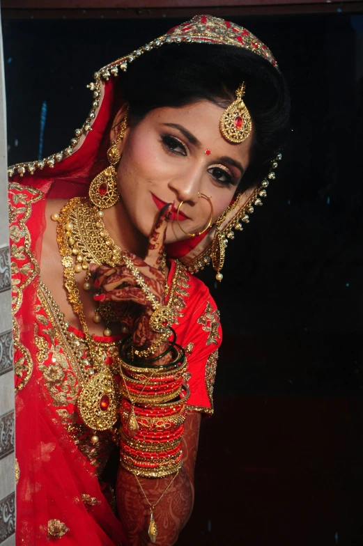 a woman wearing gold jewelry holding a finger