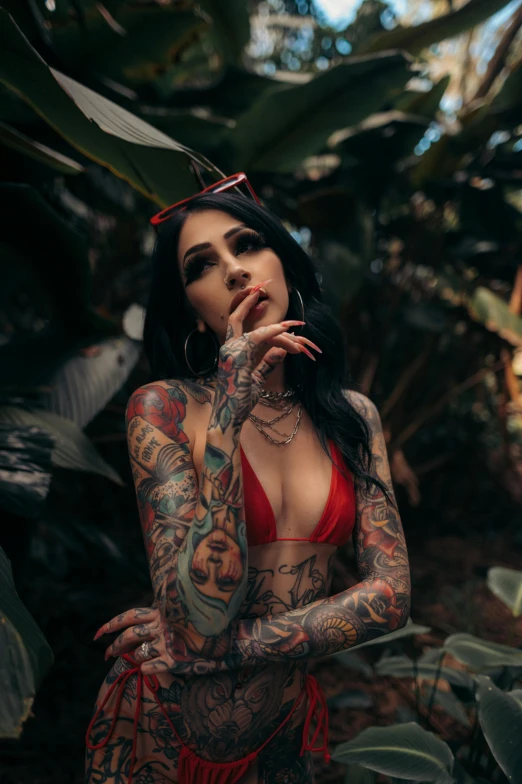 a woman with tattoos on her body, smoking a cigarette