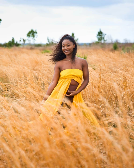 a young woman in a yellow dress standing in a tall grass field