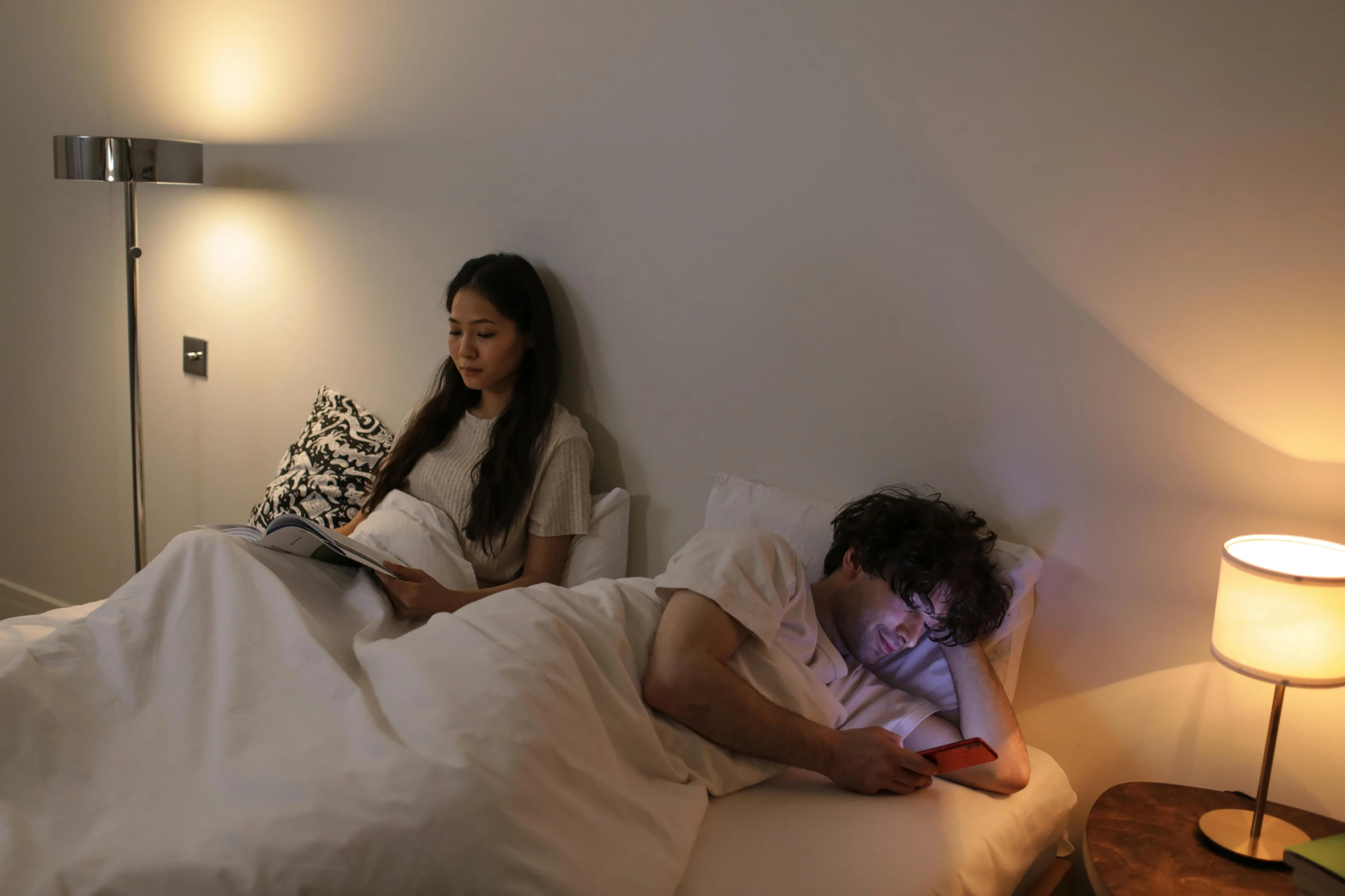 man and woman in bed reading on a tablet