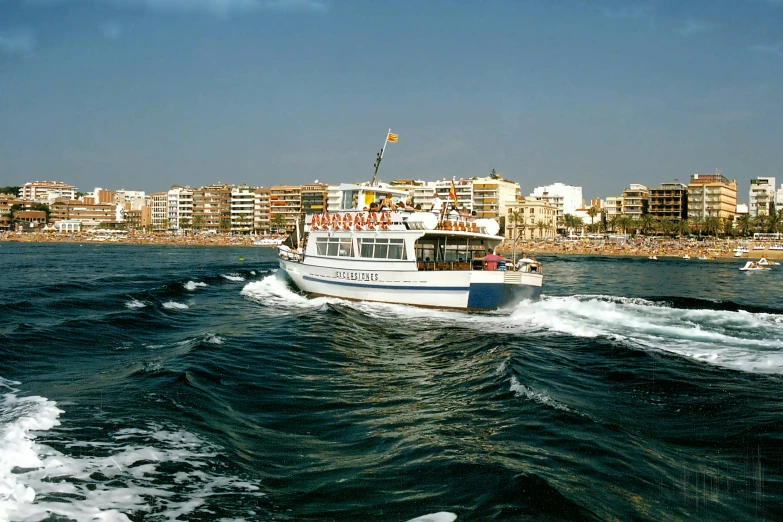 a boat traveling through the water in front of a city