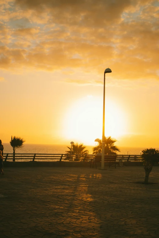 a woman and child standing on the sand looking at the sunset