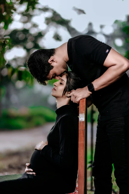 a young man kisses his beautiful girlfriend as they sit under an umbrella