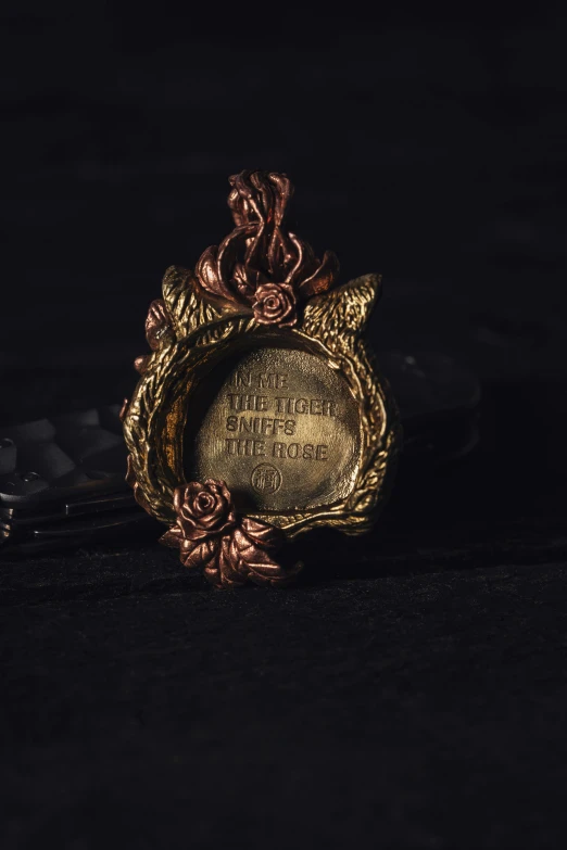 a gold pendant sits on the black surface