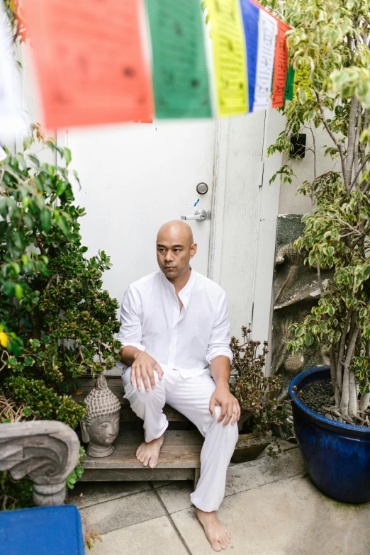 a man sits on a bench near pots and trees