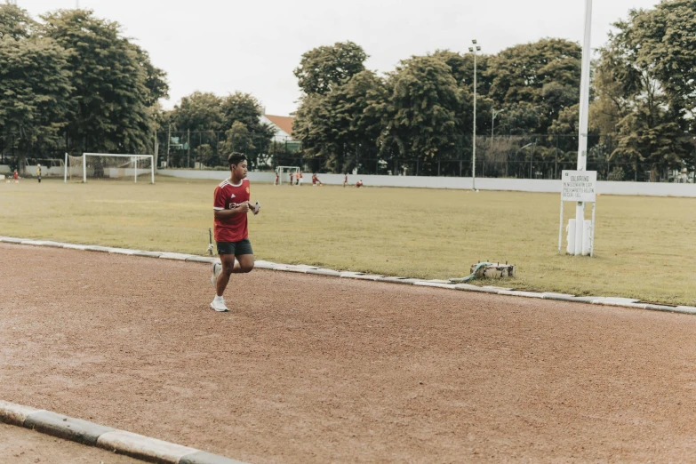 man in red shirt with black shorts running on the road