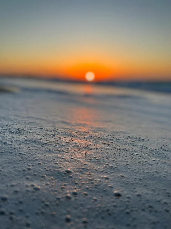 the sand is covered with tiny dots as the sun sets