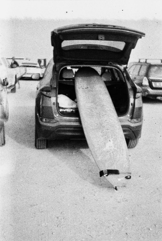 a surfer is laying on his surfboard at the back of a car