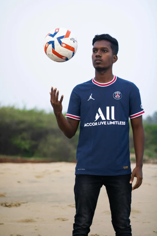 man throwing a soccer ball up on the beach