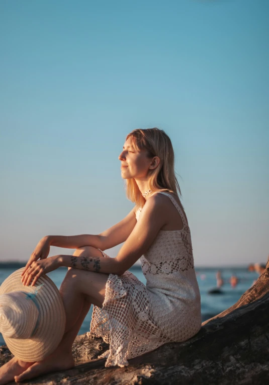 woman sitting on the beach, wearing a hat