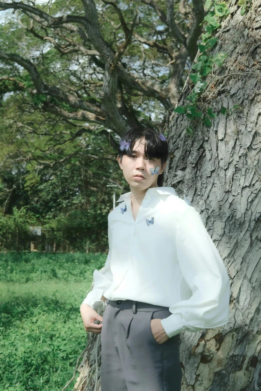 a man in a white shirt is standing near a tree