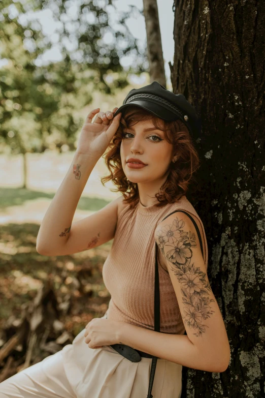 a woman with a tattooed arm leaning against a tree