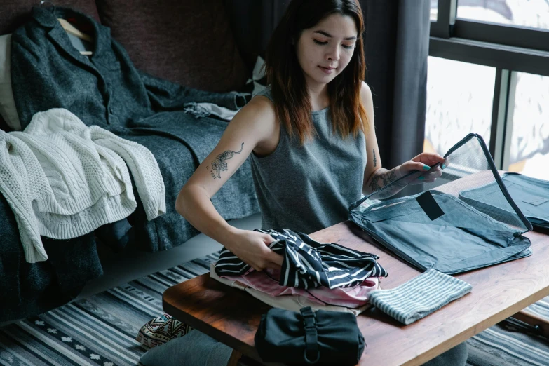 a woman sitting at a table with clothes and other items