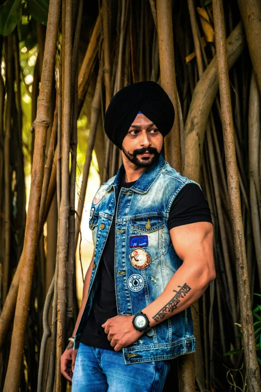 a man with a blue vest and beard standing near many tree roots