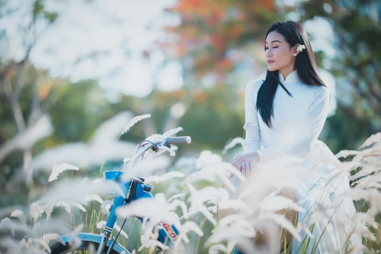 an asian woman in a white top sits near a bicycle