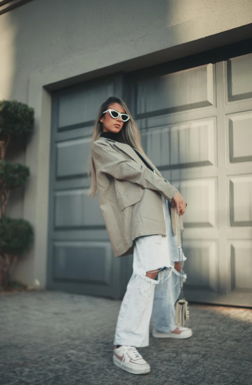 a woman in white ripped jeans is holding an open umbrella