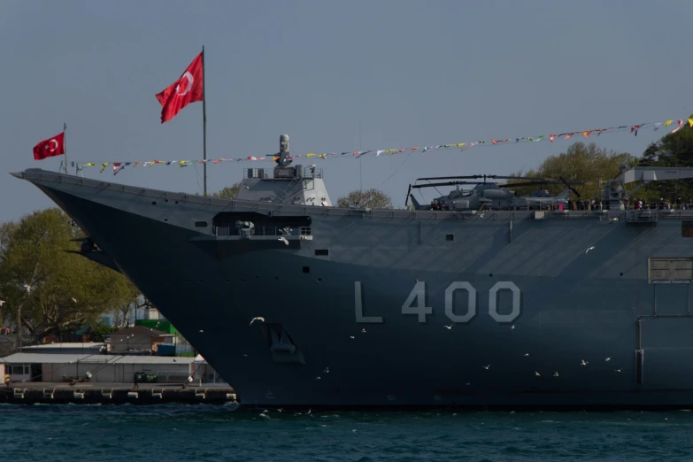 large gray boat in the middle of water with flagpole