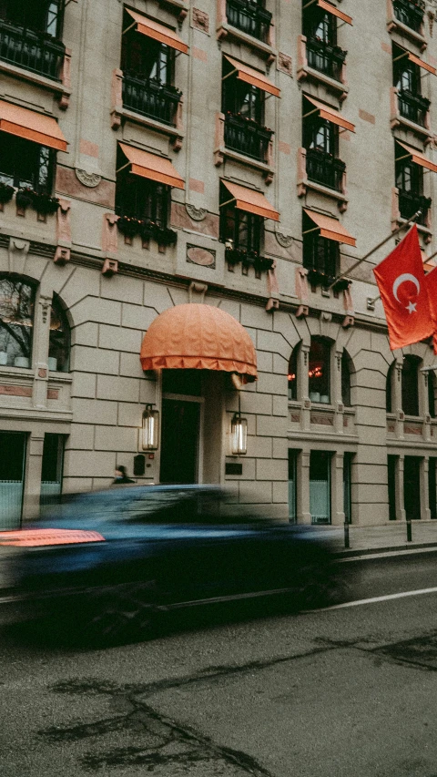 the building is grey and tall with windows and a red flag