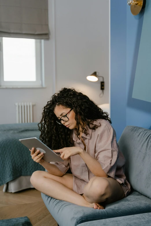 woman using tablet sitting on sofa in el room