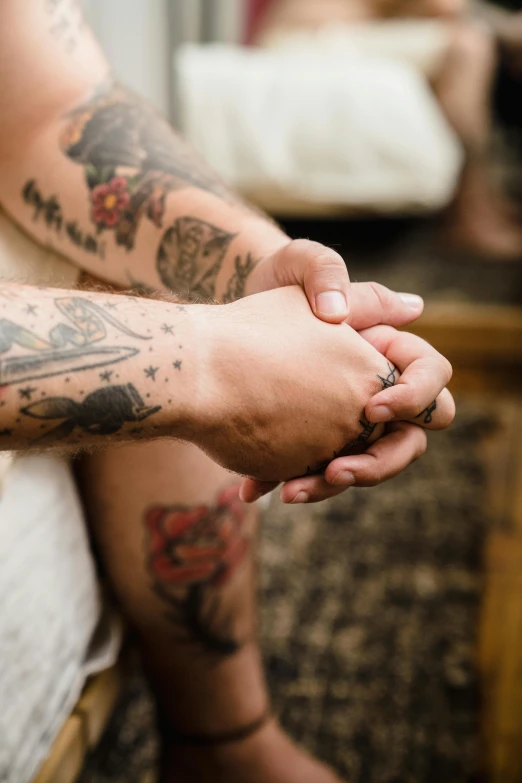 a man with a tattooed hand and wrist is sitting down