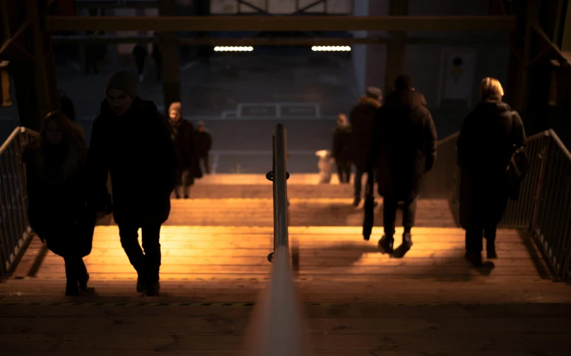 people standing on a ramp near a metal railing at night