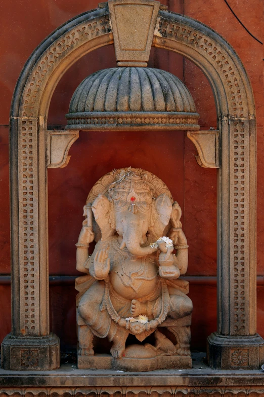 an elephant statue with one trunk extended to it's sides and an arch above it