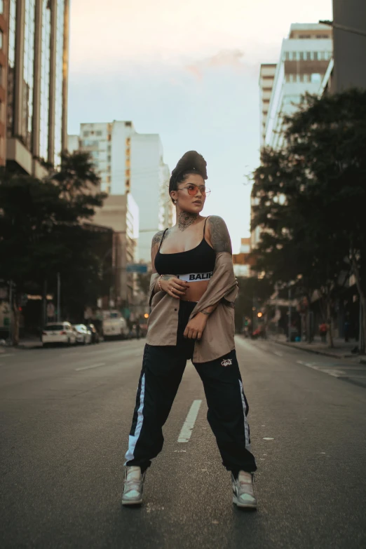 a woman in sneakers poses for a po in the middle of an empty street