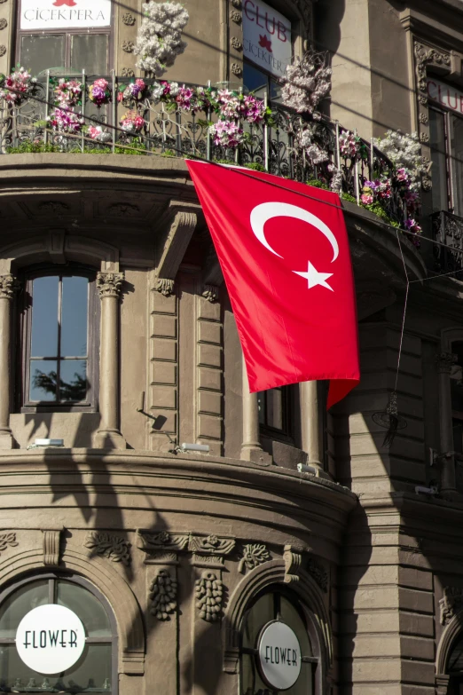 red flag waving in the wind outside a large building