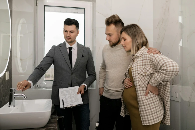 a woman standing next to two men in a bathroom