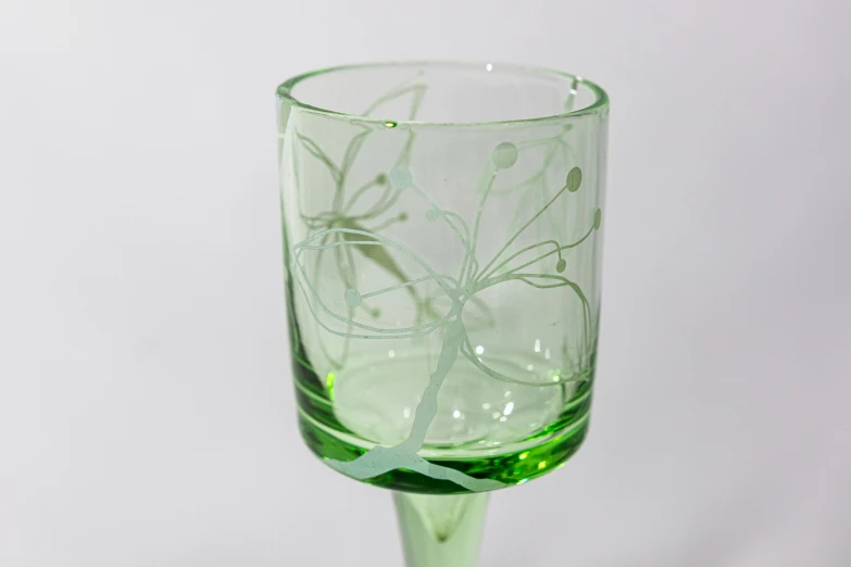 a clear stemmed glass that is green and has green flowers on it