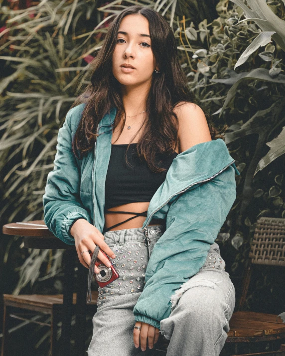 a woman sitting down next to plants in her clothes