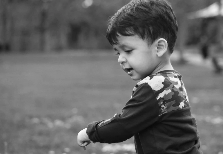 a small boy holding a baseball bat in a grassy field
