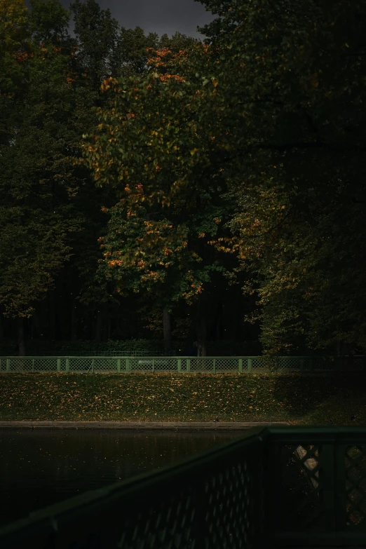 a white clock is next to the fence by trees