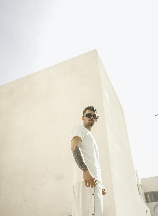 a man with glasses standing next to a white building