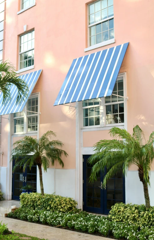 a pink and white building has trees and bushes by it