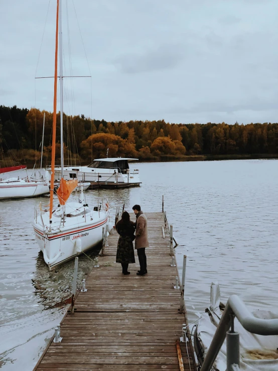 there are people standing on a dock by boats