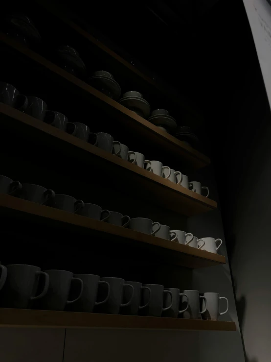 a dark room with cups on shelves on the wall