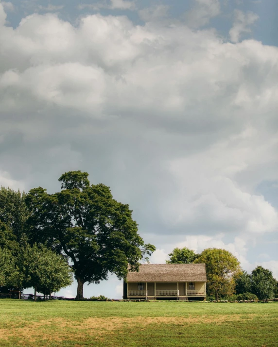 old ranch house on a grassy hill under cloudy skies